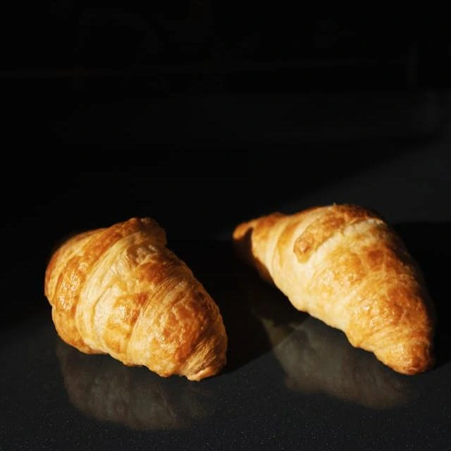 Croissant dorado y hojaldrado servido en plato blanco