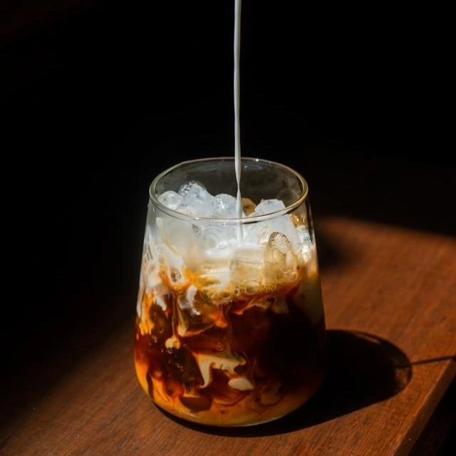 Iced latte con leche y hielo servido en vaso transparente